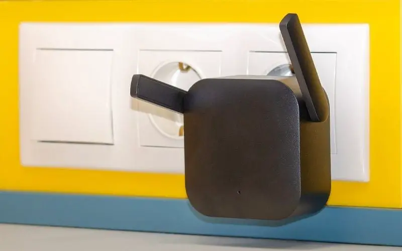 WiFi Repeater in an Electrical Outlet on a Yellow Wall